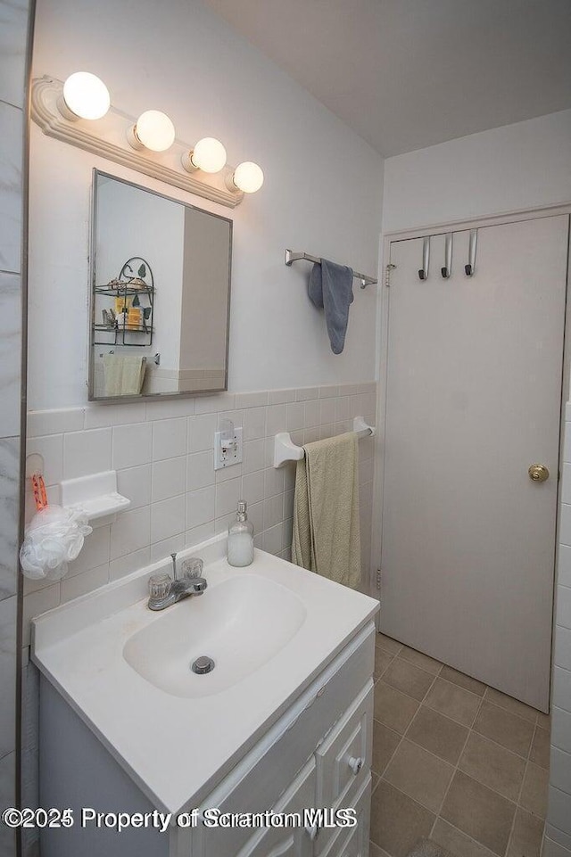 bathroom featuring a wainscoted wall, tile walls, vanity, and tile patterned flooring
