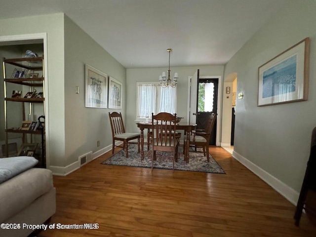 dining room featuring visible vents, baseboards, a notable chandelier, and wood finished floors
