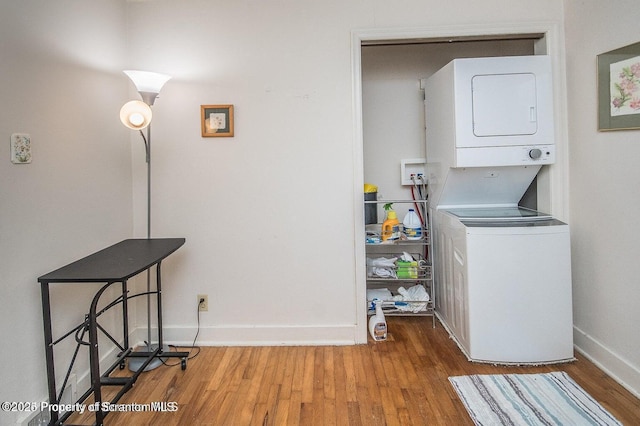laundry area with baseboards, wood finished floors, laundry area, and stacked washer / dryer