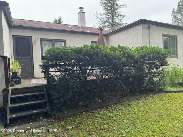 exterior space featuring a chimney and stucco siding