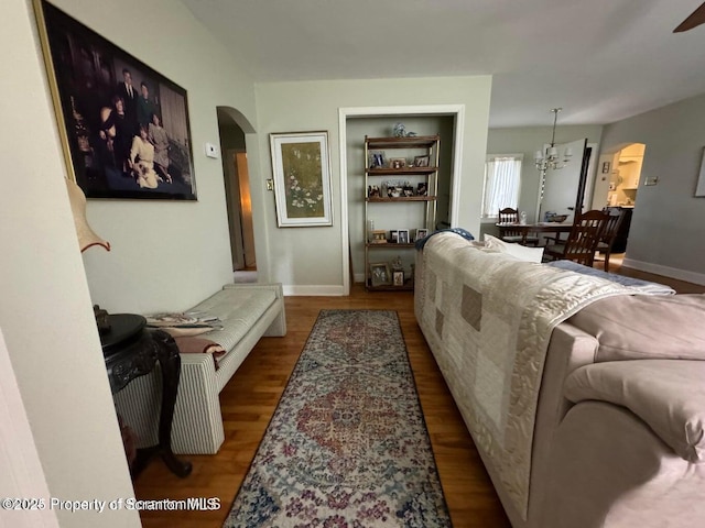 living area featuring baseboards, arched walkways, and wood finished floors