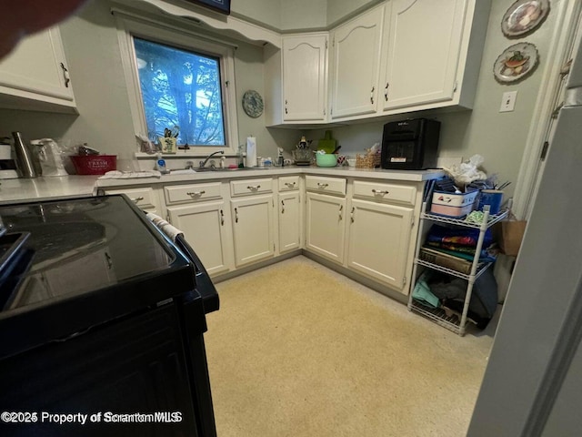 kitchen featuring white cabinets, black electric range oven, and light countertops
