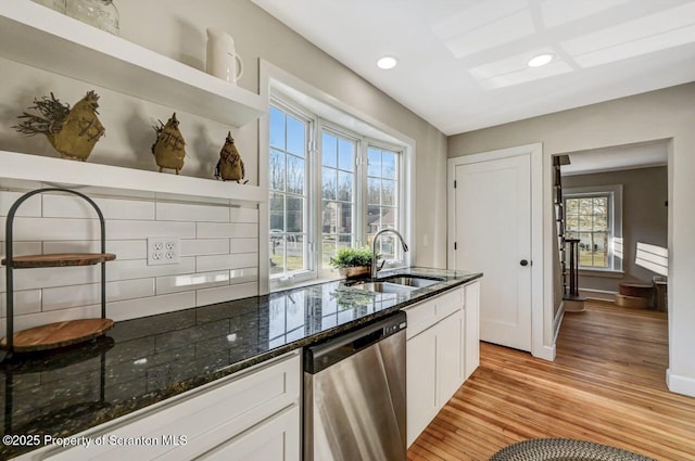 kitchen with a sink, white cabinetry, dishwasher, open shelves, and dark stone countertops