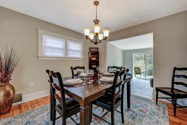 dining space with a chandelier, wood finished floors, visible vents, and baseboards