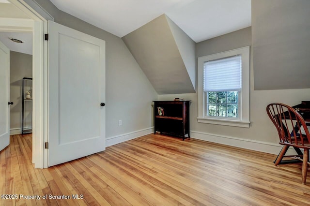 interior space featuring baseboards, vaulted ceiling, and hardwood / wood-style floors