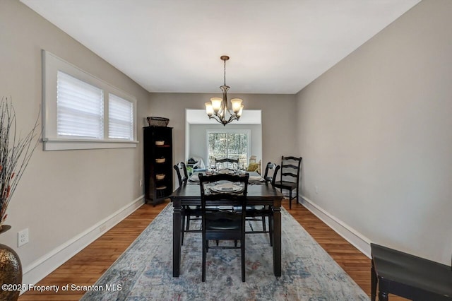 dining area with baseboards, a chandelier, and wood finished floors