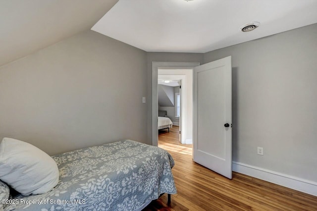 bedroom featuring visible vents, baseboards, and wood finished floors