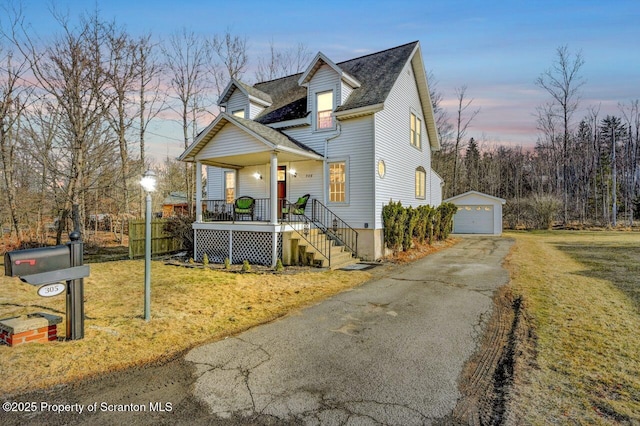 view of front of home featuring a garage, a shingled roof, aphalt driveway, an outbuilding, and a porch