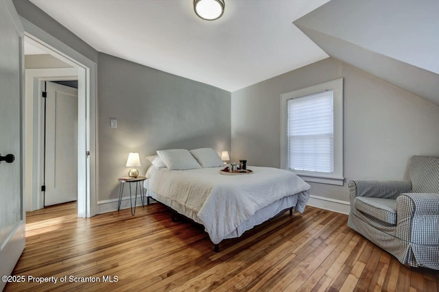 bedroom featuring wood-type flooring, baseboards, and vaulted ceiling