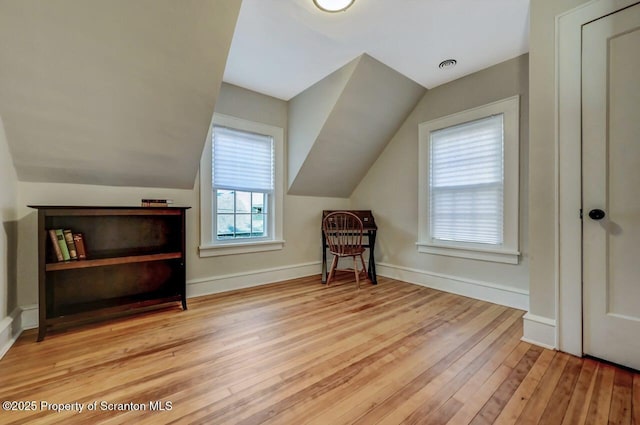 additional living space with light wood-style floors, lofted ceiling, and baseboards