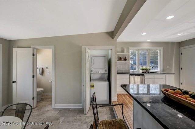 kitchen featuring recessed lighting, a sink, white cabinets, stacked washing maching and dryer, and dishwasher