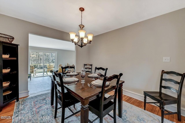 dining area featuring baseboards, a chandelier, and wood finished floors