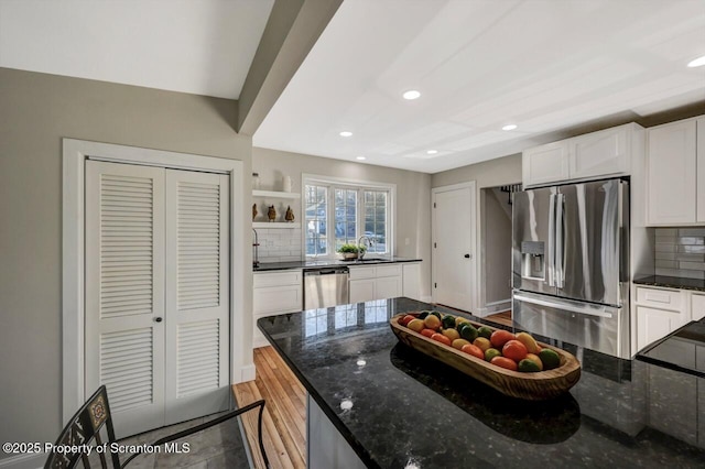 kitchen featuring white cabinets, dark stone counters, stainless steel appliances, and backsplash