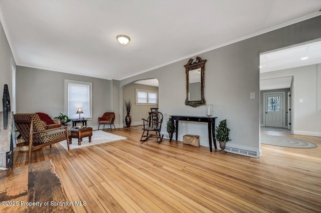 sitting room with light wood-style flooring, arched walkways, baseboards, and ornamental molding