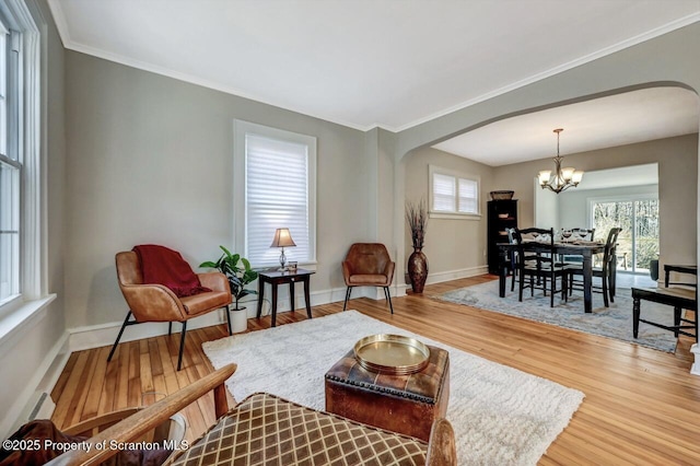 living area featuring plenty of natural light, arched walkways, a notable chandelier, and wood finished floors