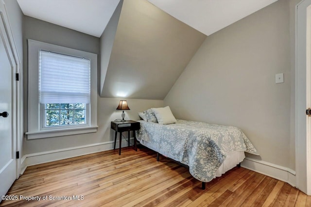 bedroom with lofted ceiling, baseboards, and hardwood / wood-style floors