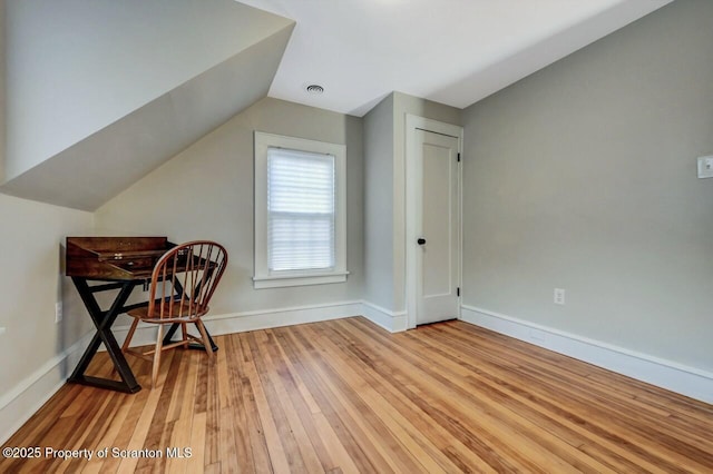 interior space with lofted ceiling, visible vents, light wood-style flooring, and baseboards