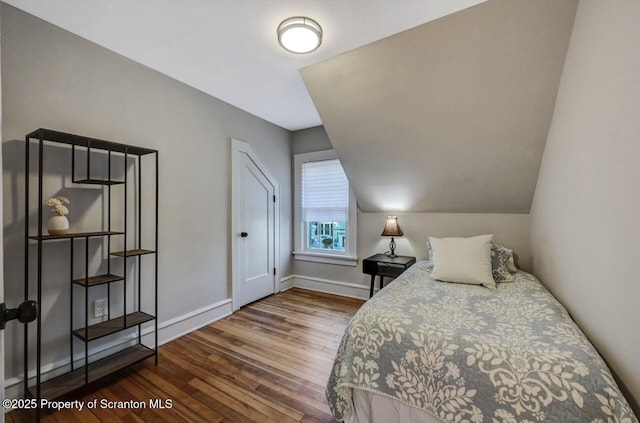 bedroom with lofted ceiling, baseboards, and wood finished floors