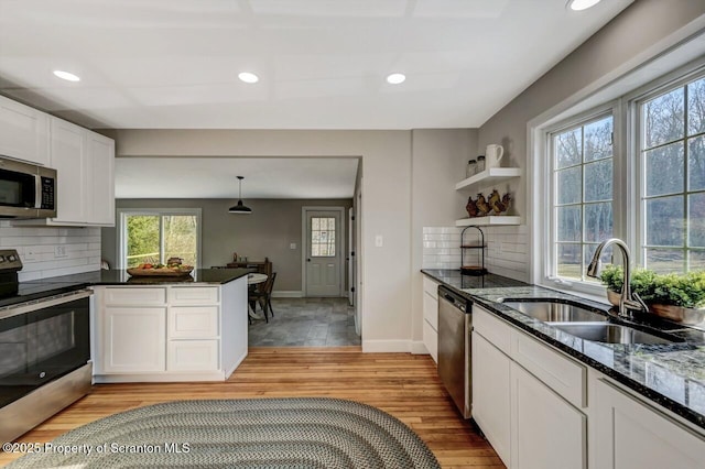 kitchen with stainless steel appliances, recessed lighting, light wood-style floors, white cabinetry, and a sink