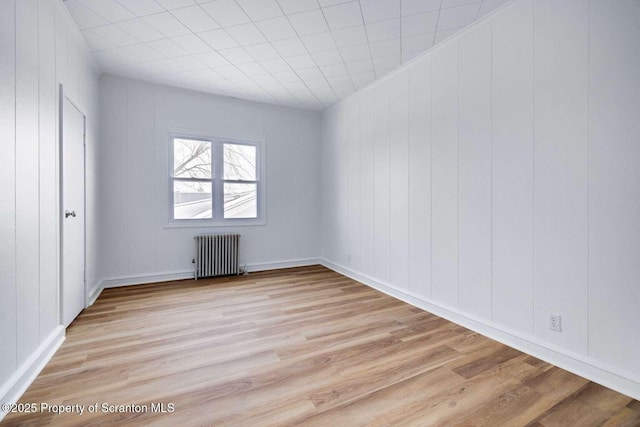 unfurnished room with radiator heating unit and light hardwood / wood-style floors