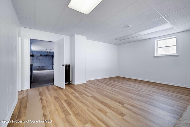 spare room with a drop ceiling and light wood-type flooring