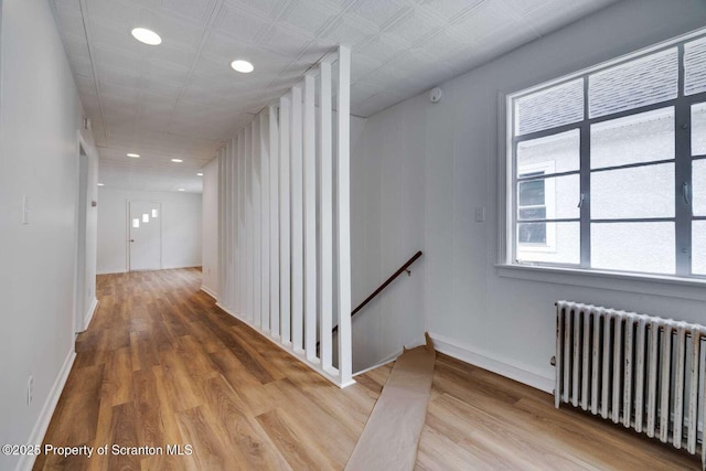 corridor featuring wood-type flooring and radiator