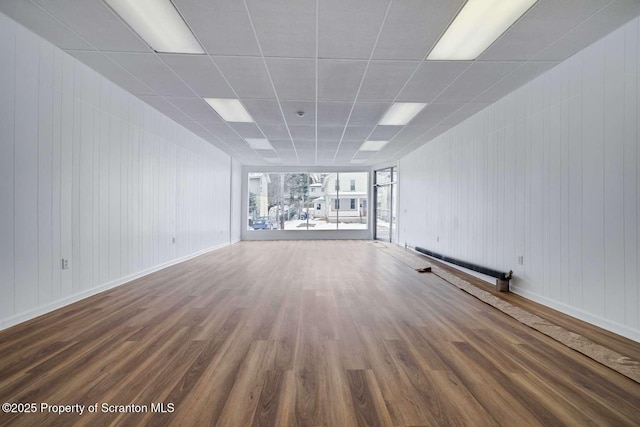 unfurnished living room featuring wood-type flooring and a drop ceiling