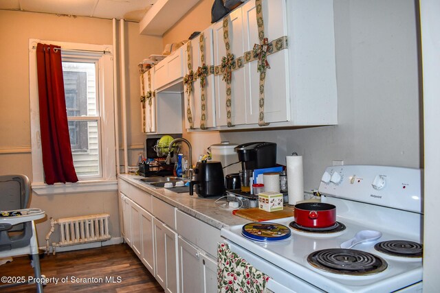 kitchen with a sink, radiator heating unit, light countertops, white cabinets, and electric stove