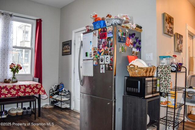 kitchen featuring black microwave, freestanding refrigerator, and wood finished floors