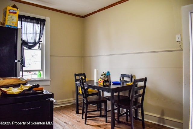 dining space featuring ornamental molding and wood finished floors