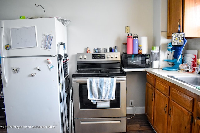 640 Alder St, Scranton, PA 18505 - kitchen featuring freestanding refrigerator, electric range, black microwave, brown cabinetry, and light countertops