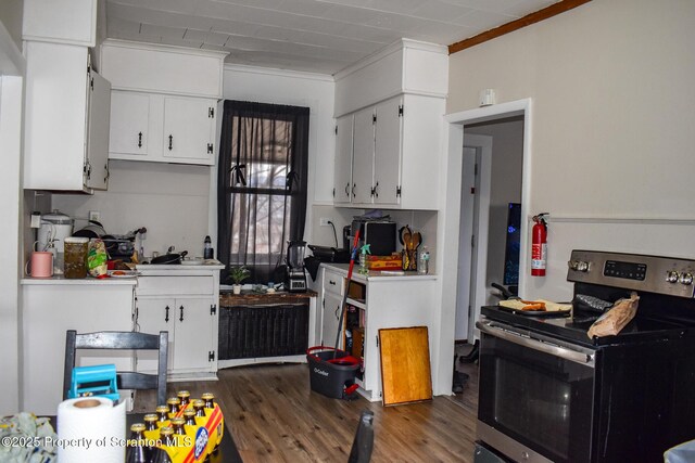 kitchen featuring crown molding, stainless steel electric range, wood finished floors, light countertops, and white cabinetry