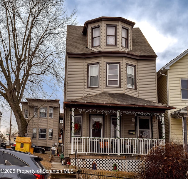 second empire-style home with a porch and a shingled roof