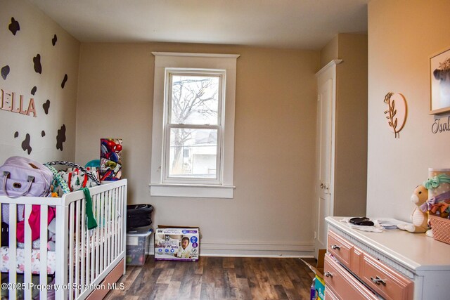 bedroom with a crib and dark wood finished floors