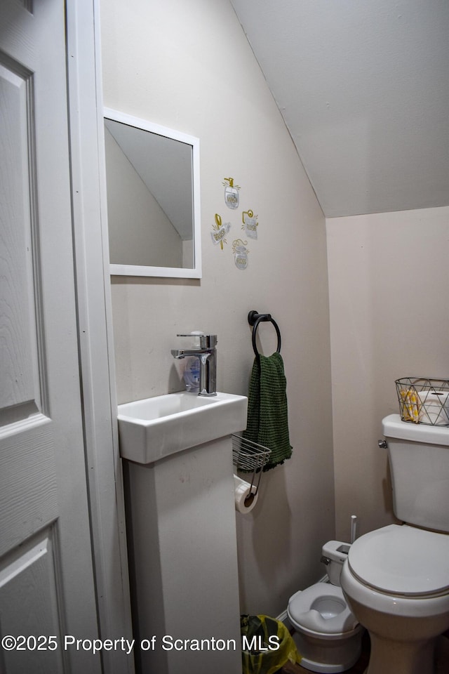 half bath featuring vanity, toilet, and lofted ceiling