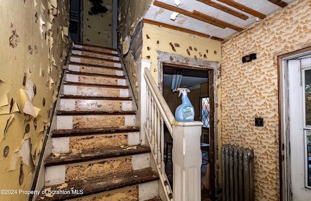 stairway featuring beam ceiling and radiator