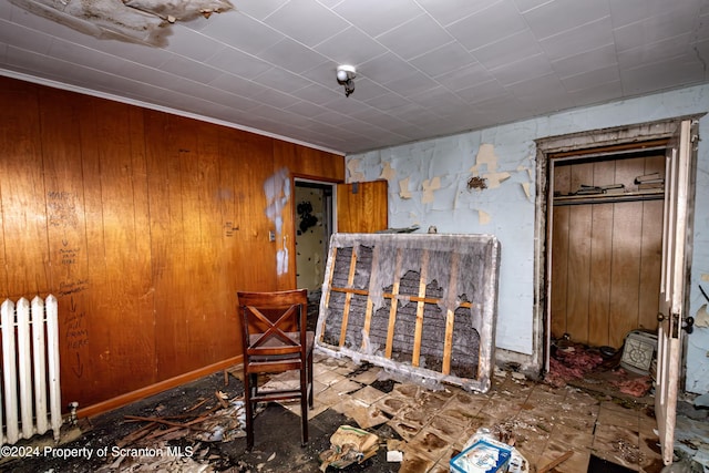 interior space featuring radiator heating unit, crown molding, and wooden walls