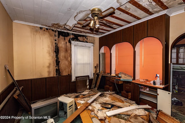 miscellaneous room with wood walls, ceiling fan, and ornamental molding