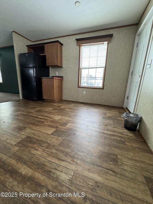 kitchen with black fridge, crown molding, and dark hardwood / wood-style floors