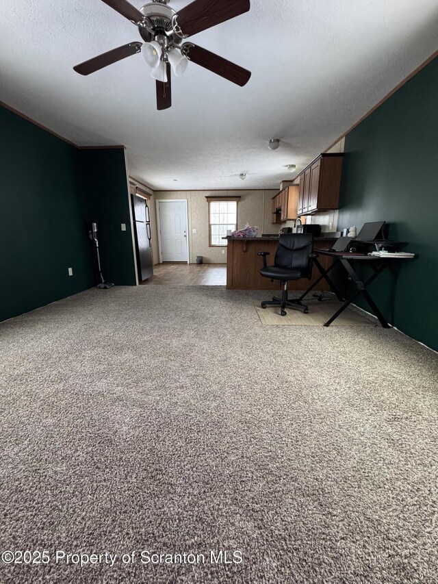 carpeted office space featuring ceiling fan and crown molding