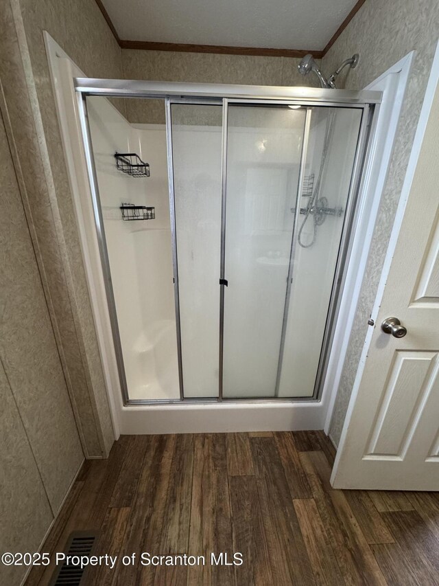 bathroom with a shower with door, wood-type flooring, and ornamental molding