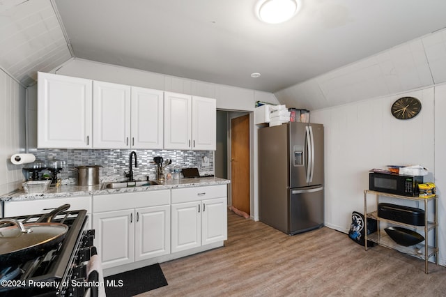 kitchen with stainless steel appliances, white cabinetry, lofted ceiling, and sink