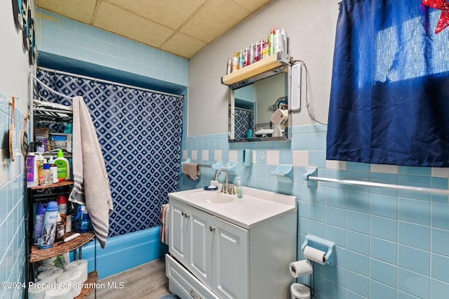 bathroom featuring a paneled ceiling, vanity, and tile walls