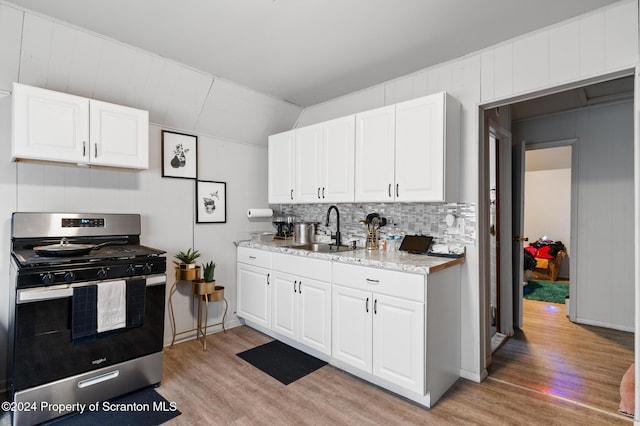 kitchen with light hardwood / wood-style flooring, white cabinetry, stainless steel gas range oven, and sink