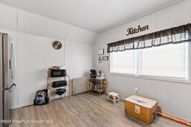 miscellaneous room featuring wooden walls, radiator heating unit, hardwood / wood-style floors, and vaulted ceiling