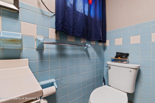 bathroom with vanity, toilet, and tile walls