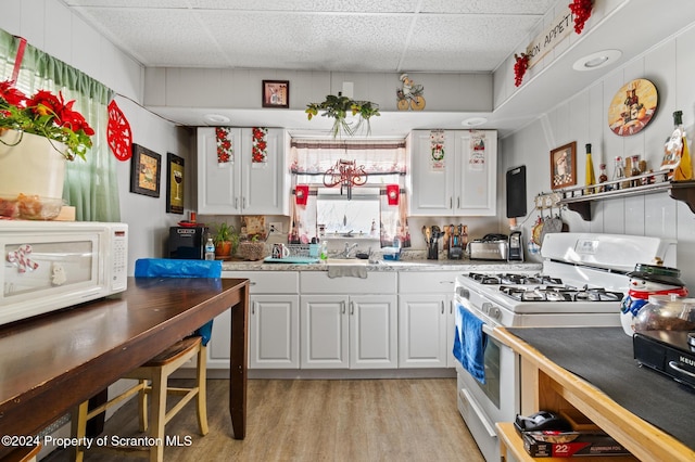 kitchen with white appliances, light hardwood / wood-style floors, white cabinetry, and a drop ceiling