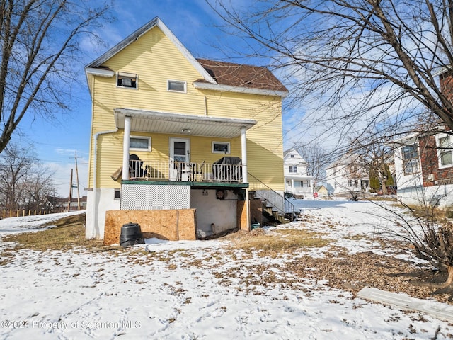 snow covered rear of property with a porch