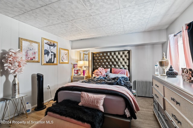 bedroom featuring radiator heating unit and light wood-type flooring