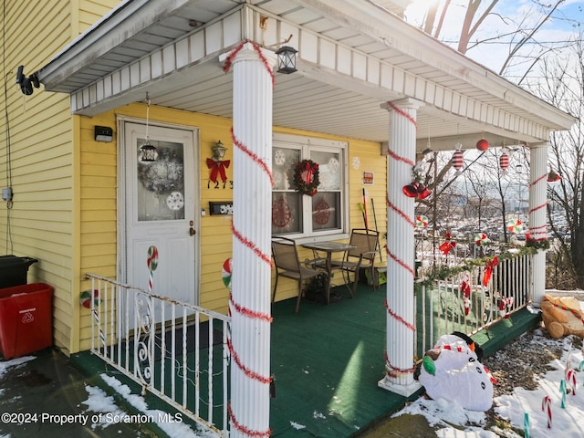 snow covered property entrance with a porch